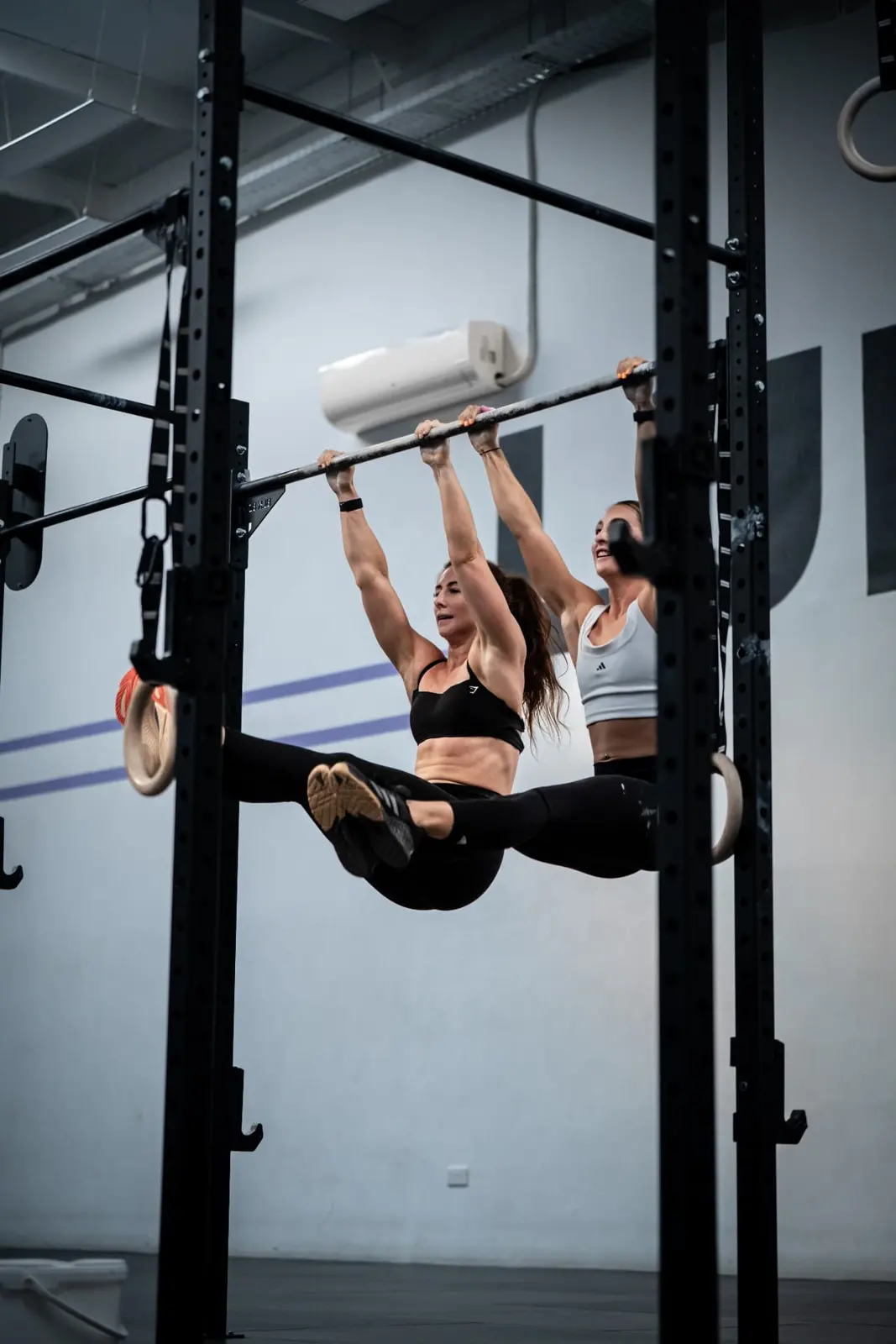 Two athletes performing hanging leg raises on a rig