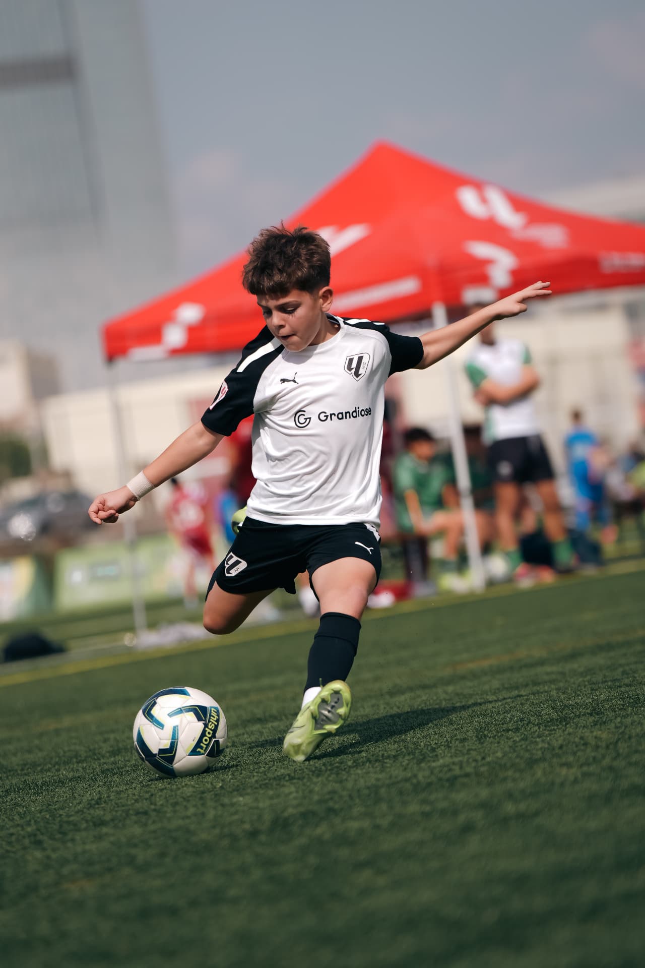 Young footballer striking the ball in a Grandiose kit