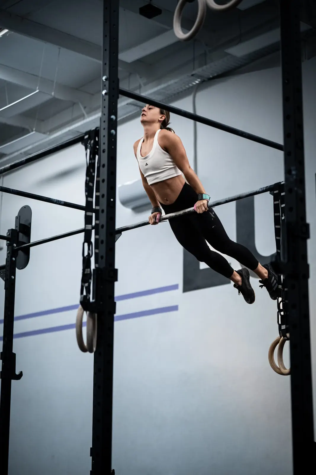 Athlete mid bar muscle-up in a gym