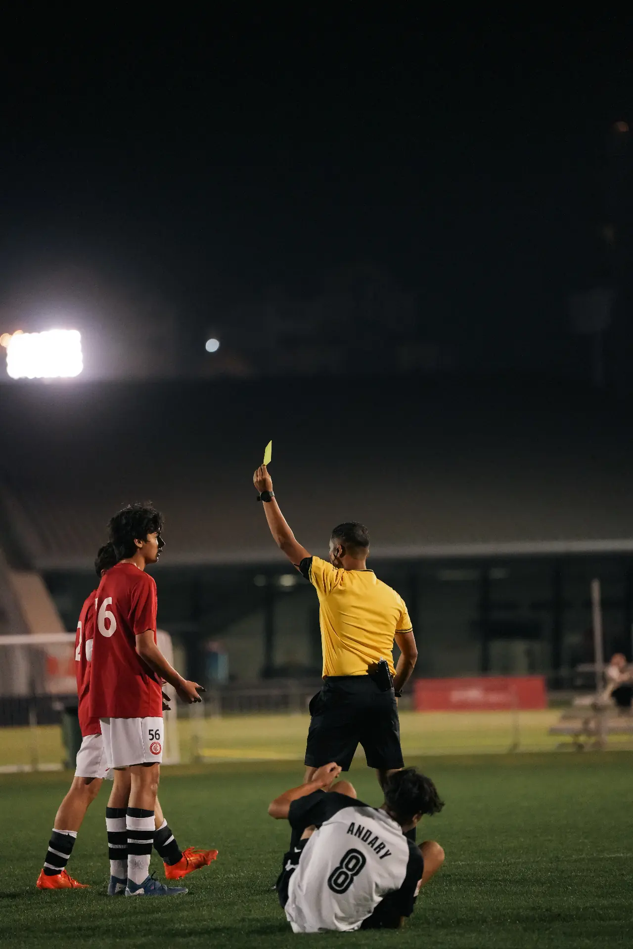 Referee issuing a yellow card under stadium lights